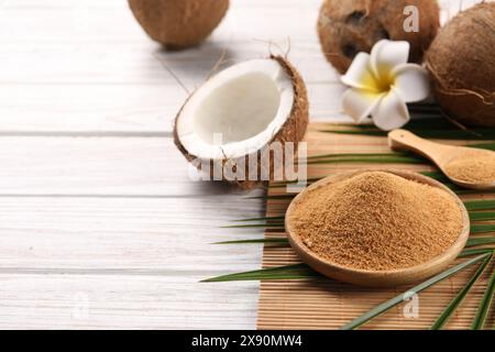 Kokoszucker, Palmblätter, Früchte und Bambusmatte auf rustikalem Holztisch, Nahaufnahme. Leerzeichen für Text Stockfoto