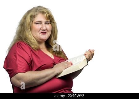 Dieses Bild fängt einen fröhlichen Moment einer 50-jährigen weißen Frau mit blonden Haaren ein, die ein Buch liest und die Kamera anlächelt. Stockfoto