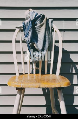 Alte und dreckige blaue Jeans, die auf dem Holzstuhl auf der Terrasse lag Stockfoto