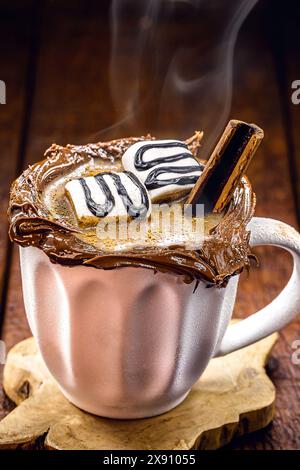 Vegane heiße Schokolade im weißen rustikalen Becher, Holzhintergrund und Rauch, heißer Winterdrink Stockfoto