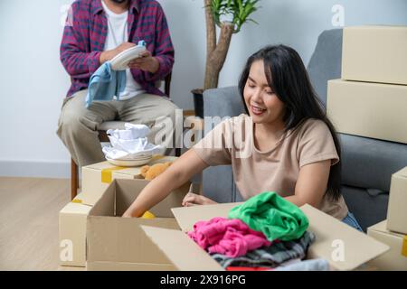 Das junge Paar hilft sich gegenseitig dabei, Haushaltsgegenstände zu packen, um sich auf den Umzug in ihr neues Zuhause vorzubereiten Stockfoto