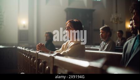 Gruppe treuer Pfarrer in der Großen alten Kirche, die Predigt hören. Die fromme christliche Lady mit gefalteten Händen betet. Die Menschen suchen moralische Führung von der Religios-Fait am heiligen Ort Stockfoto