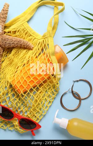 Schnur-Tasche, verschiedene Strandzubehör und Palmblatt auf hellblauem Hintergrund, flache Lay Stockfoto