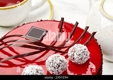 Kuchen mit roter Glasur, Schokoladenstrudel und Kokos-Trüffel mit Tee Stockfoto