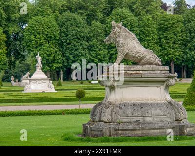 Steinskulptur eines Wildschweins in einem weitläufigen Park mit Hecken und Bäumen, historisches Schloss mit grünem Park mit Skulpturen und Wegen, nordkirchen, deutschland Stockfoto