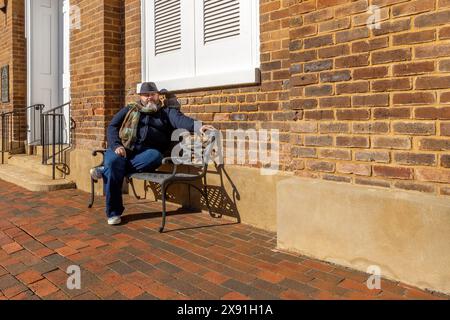 Ein Mann mit Hut und Schal mit Bart sitzt auf einer Metallbank im historischen Greenville, Tennessee, USA Stockfoto