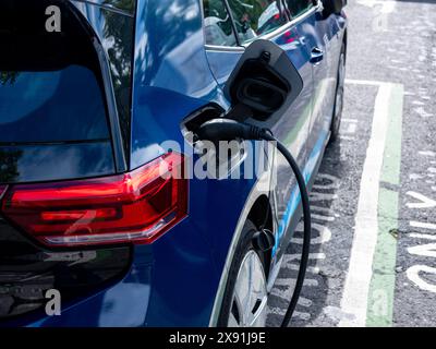 Ein Elektroauto parkt an einer Ladestation für Elektrofahrzeuge auf der Straße. Stockfoto