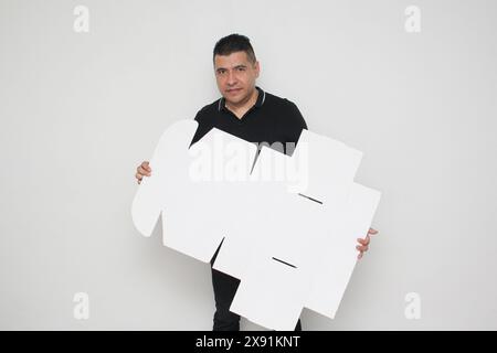 Ein Erwachsener Latino baut einen Karton nach den Anweisungen zusammen, um ihn zu erreichen Stockfoto