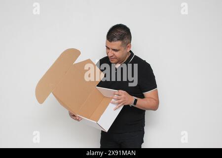 Ein Erwachsener Latino baut einen Karton nach den Anweisungen zusammen, um ihn zu erreichen Stockfoto