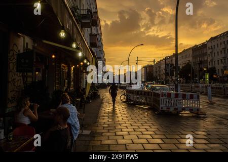 Abendhimmel nach einem Regenschauer über der Danziger Straße mit Gästen vor einem Späti sitzend in der Danziger Straße in Berlin-Prenzlauer Berg. / Abendhimmel nach einem Regenschauer über der Danziger Straße mit Gästen, die vor einem Nachtladen in der Danziger Straße in Berlin-Prenzlauer Berg sitzen. Späti *** Abendhimmel nach einem Regenschauer über der Danziger Straße mit Gästen, die vor einem Late Night Store in der Danziger Straße in Berlin Prenzlauer Berg Späti snph202405255385.jpg sitzen Stockfoto