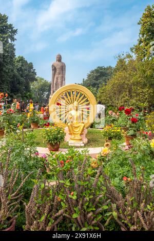 Varanasi, Indien - 24. Februar 2024: Dharma-Chakra-Statue des goldenen Buddha im Rad im Blumenpark in Sarnath. Uttar Pradesh, Varanasi, Indien Stockfoto