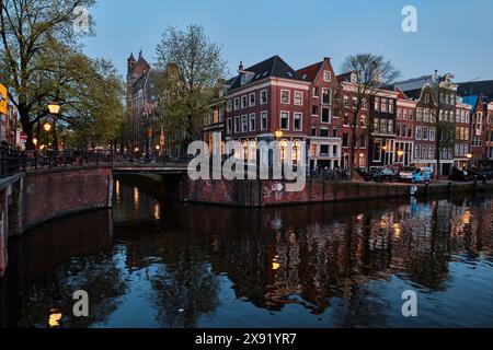 Niederlande, Amsterdam - 10. April 2024: Amsterdamer Grachtenhäuser, Fahrräder und Brücken in der Abenddämmerung im Stadtteil Jordaan Stockfoto