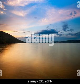 Eine ruhige Abendszene über der Embalse de Puente Nuevo mit leuchtend blauem Himmel und Silhouette der Berge. Stockfoto