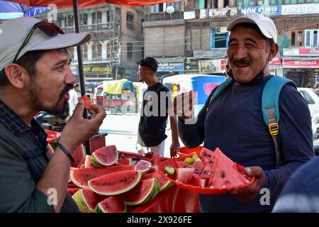 Srinagar, Indien. Mai 2024. Pendler essen an einem sengenden Sommertag Wassermelonen an einem Straßenstand. Das Kaschmir-Tal erlebte einen deutlichen Temperaturanstieg, wobei mehrere Gebiete die höchsten Temperaturen seit Jahrzehnten aufwiesen. Die Meteorologische Abteilung prognostizierte die Fortsetzung der Hitzewelle auch im nächsten Monat. (Credit Image: © Saqib Majeed/SOPA Images via ZUMA Press Wire) NUR REDAKTIONELLE VERWENDUNG! Nicht für kommerzielle ZWECKE! Stockfoto