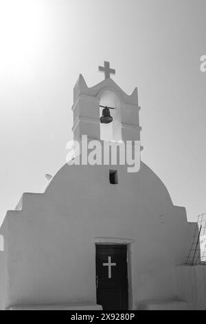 Blick auf eine wunderschöne weiß getünchte orthodoxe Kapelle mit einer Glocke und einem Kreuz auf der Spitze in iOS Griechenland Stockfoto