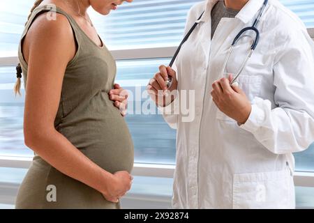 Der Arzt steht vor seiner 7 Monate schwangeren Patientin. Dialog einer schwangeren Frau mit ihrem Arzt. 016644 037 Stockfoto