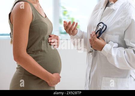 Der Arzt steht vor seiner 7 Monate schwangeren Patientin. Dialog einer schwangeren Frau mit ihrem Arzt. 016644 038 Stockfoto