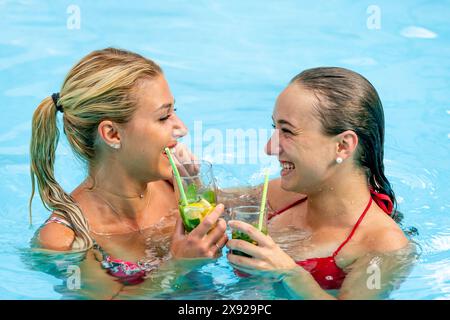 Zwei Freunde, die Spaß im Swimmingpool haben und eine eisgekühlte Minzzitronenentspannung im Pool von zwei Freundinnen genießen 016644 142 Stockfoto