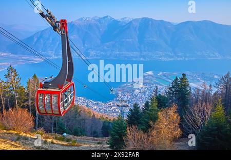 Die moderne rote Seilbahn des Orselina Cardada Mount liegt am Lago Maggiore und den trüben Alpen, ein Blick vom Hang der Cardada Cimetta, Tessin, Schweiz Stockfoto