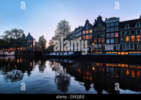 Niederlande, Amsterdam - 10. April 2024: Amsterdamer Grachtenhäuser, Fahrräder und Brücken in der Abenddämmerung im Stadtteil Jordaan Stockfoto