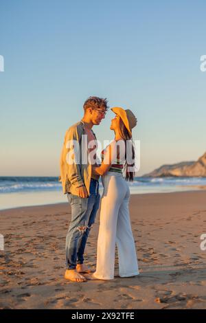 Vertikal Ein romantischer Moment, in dem ein multikulturelles hispanisches Paar sich liebevoll in die Augen des anderen am Strand während eines wunderschönen Sommers blickt Stockfoto