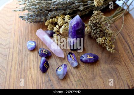 Skandinavische Runen aus Amethysten, Halbedelsteinkristallen und trockenen Kräutern. Vorhersagen, Hexerei, spirituelle esoterische Praxis. Stockfoto