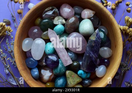 Schöne natürliche Halbedelsteine und trockene Kräuter auf einem violetten Hintergrund. Vorhersagen, Hexerei, spirituelle esoterische Praxis. Stockfoto