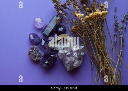 Schöne Drusen und Amethyst-Kristalle und trockene Kräuter auf einem lila Hintergrund. Vorhersagen, Hexerei, spirituelle esoterische Praxis. Stockfoto