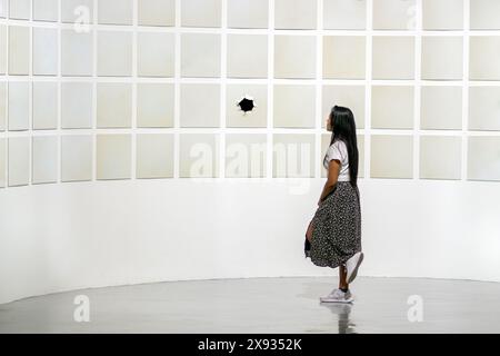 Eine junge Frau schaut sich eine Ausstellung moderner Kunst an Stockfoto