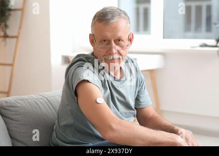 Seniorin mit Glukosesensor zur Messung des Blutzuckerspiegels zu Hause. Diabeteskonzept Stockfoto