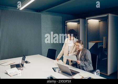 Zwei weibliche Kollegen diskutieren das Projekt, bevor sie der Teamleiterin im Büro eine Präsentation zeigen Stockfoto