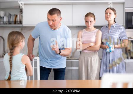 Ein junges Mädchen, das missbilligende Worte von Vater, Mutter und älterer Schwester hört Stockfoto