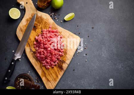 Geschnittenes und gehacktes Thunfischfilet auf hölzernem Schneidebrett in der Hausküche, die traditionelles Tatar kocht Stockfoto