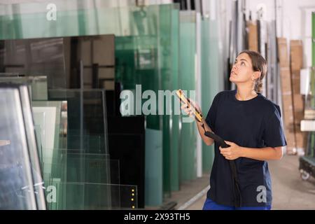 Junge Frau, die Maschinen mit Fernbedienung in der Glasfabrik bedient Stockfoto