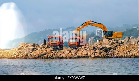 Wellenbrecherbau an der Seeküste. Bagger gießt Steine in Lkws. Problemumgehung. Batumi, Georgien. Hochwertige Fotos Stockfoto