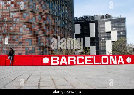 Ein Jugendlicher hört einem Mobiltelefon bny ein massives rot gemaltes Barcelona-Logo, das im April 2024 im OFFF Barcelona im Disseny Hub Museum of Design in Barcelona, Spanien, an einer Wand gemalt wurde. Bild: Rob Watkins. INFO: Die beliebte Jahreskonferenz wurde 2001 ins Leben gerufen und ist die weltweit größte Ausstellung zeitgenössischer visueller Kreativität und Design. Es zieht Designer, Künstler, Filmemacher und Fotografen aus der ganzen Welt an und dient als globale Plattform für kreativen Austausch und Zusammenarbeit. Stockfoto