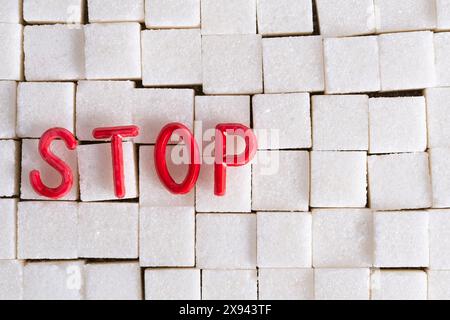 WORTSTOPP in roten Buchstaben auf weißen Zuckerwürfeln im Hintergrund, die die Botschaft gegen den Zuckerkonsum betonen Stockfoto