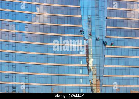 Baku. Aserbaidschan. 09.27.2021. Leute an hängenden Kabeln waschen die Fenster des Hotels. Stockfoto