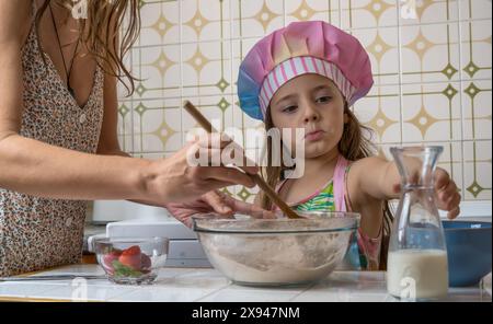 Ein Mädchen, verkleidet als Koch, genießt einen Nachmittag mit ihrer Mutter Stockfoto