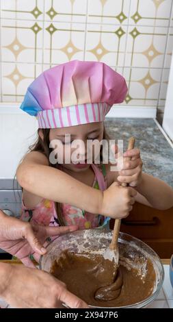 Ein Mädchen, verkleidet als Koch, genießt einen Nachmittag mit ihrer Mutter Stockfoto