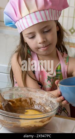 Ein Mädchen, verkleidet als Koch, genießt einen Nachmittag mit ihrer Mutter Stockfoto