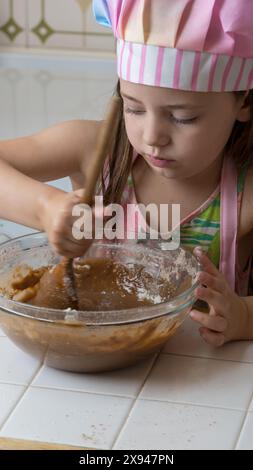 Ein Mädchen, verkleidet als Koch, genießt einen Nachmittag mit ihrer Mutter Stockfoto