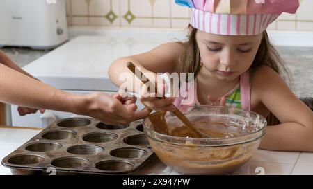 Ein Mädchen, verkleidet als Koch, genießt einen Nachmittag mit ihrer Mutter Stockfoto