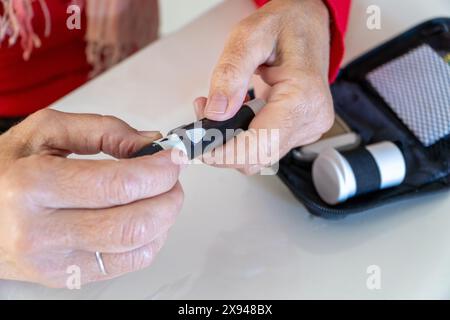 Diabetespatientin bei Wahl der Punktionstiefe des Stechstifts auf einem Blutzuckermesssystem Stockfoto