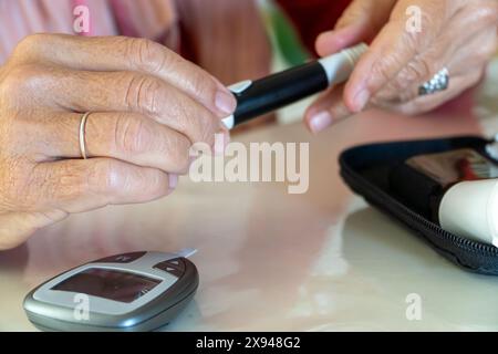 Seniorin wählt die Punktionstiefe des Stechstifts des Glukosetests Stockfoto