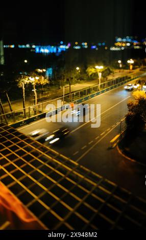 Baku, Aserbaidschan - 3. Mai 2019: Nächtliche Luftaufnahme von Baku mit einem neigbaren Objektiveffekt, der verschwommene Autos auf der Straße, beleuchtete Straßenlaternen und Rolex-Banner aus einer kürzlichen F1-Meisterschaft zeigt Stockfoto