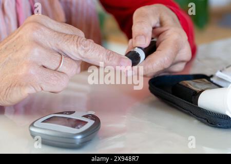 Detail des Punktionszeitpunktes mit dem Stock am Finger vor der Prüfung des Zuckerspiegels auf einem Glukosemonitorsystem Stockfoto