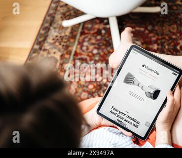 Paris, Frankreich - 11. Juni 2023: Eine Frau sitzt und surft auf einem iPad auf der Apple-Website und sieht die Vision Pro Produktseite mit dem Slogan Freigeben Sie Ihren Desktop. Und Ihre Apps werden folgen. Stockfoto