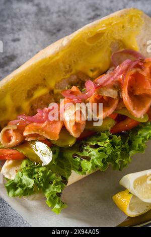 Sandwich mit geräuchertem Lachs auf Metallteller auf Steintisch Stockfoto
