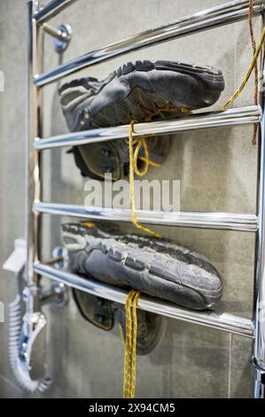 Wanderschuhe trocknen nach dem großen Camping. Schwarze Stiefel zum Wandern, liegen auf dem Trockner im Badezimmer. Stockfoto